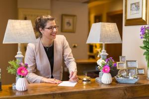 una mujer sentada en un escritorio con flores en Hôtel-Restaurant Ricordeau en Loué