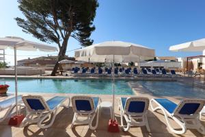 a swimming pool with chairs and an umbrella at Hotel Clumba in Cala Ratjada