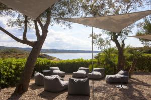 a patio with chairs and an umbrella and a lake at Hotel Es Blau Des Nord in Colonia de Sant Pere