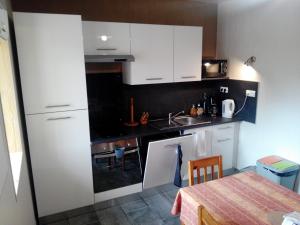 uma pequena cozinha com armários brancos e uma mesa em Gîte familial -- Les KIWIS em Gémozac