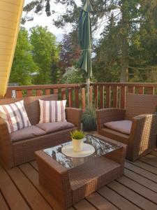 eine Terrasse mit Korbstühlen, einem Tisch und einem Sonnenschirm in der Unterkunft Gästehaus Alwine Wohnung 6 in Grömitz