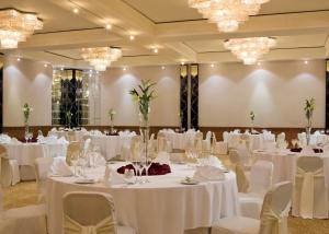 un salón de banquetes con mesas y sillas blancas y lámparas de araña en Sheraton Bahrain Hotel, en Manama