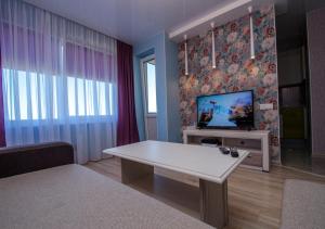 a living room with a white table and a tv at Poruka apartamenti in Ventspils