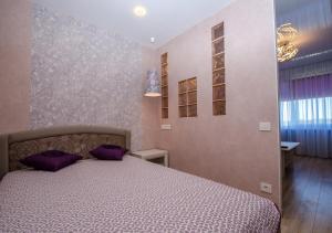a bedroom with a bed with purple pillows on it at Poruka apartamenti in Ventspils