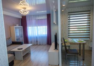 a living room with a couch and a table with a tv at Poruka apartamenti in Ventspils