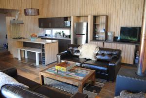 a living room with a leather couch and a table at Casa Negra Nevados de Chillan in Las Trancas