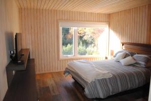 a bedroom with a bed and a large window at Casa Negra Nevados de Chillan in Las Trancas