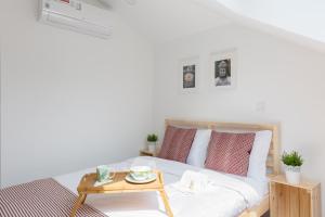 a white bed with red pillows and a table at APOSENTUS - Your home at Pinheiro's Residence in Porto