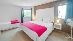 a bedroom with a large white bed with a red blanket at Valentina Suites by Las Flores Vacation Rentals in Playa del Carmen
