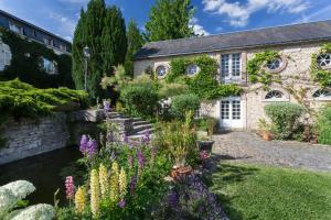 un jardin en face d'une maison en pierre ornée de fleurs dans l'établissement Hôtel-Restaurant Ricordeau, à Loué