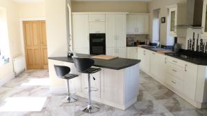 a kitchen with white cabinets and a black counter and stools at Emy Lakehouse - near Castle Leslie, Glaslough in Monaghan