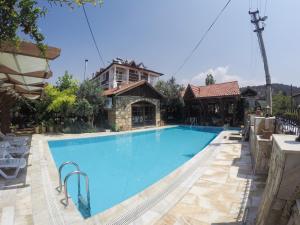 a large swimming pool with a house in the background at Melrose Pansiyon in Pamukkale