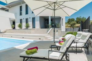 patio z krzesłami i parasolem przy basenie w obiekcie Villa Franica Zadar w mieście Zadar