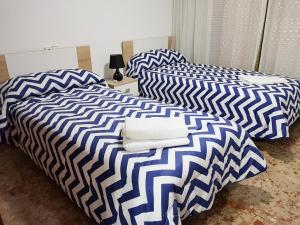 duas camas com lençóis azuis e brancos num quarto em Apartamento Completo Maravall Centro em Benidorm