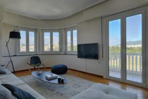 a living room with a couch and a tv and windows at Athens Grand Suite in Athens