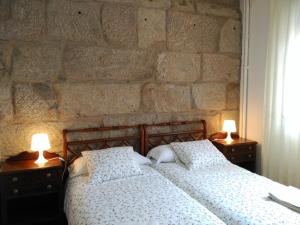 1 dormitorio con pared de piedra, 2 camas y lámparas en A casa de Carmiña en Gondomar