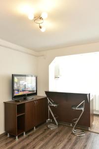 a living room with a flat screen tv on a wooden cabinet at The Home in Hunedoara