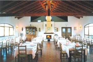 a dining room with white tables and chairs and a fireplace at Agriturismo Le Due Cascine in San Marzano Oliveto