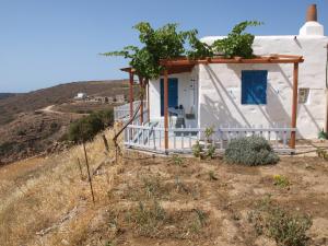 a small white house with a blue door on a hill at Alatsaria House in Cherronisos