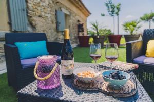 a table with a bottle of wine and two glasses at Maison Sadina in Séguret