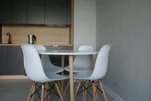 a kitchen with a table and four white chairs at Caroline Street nine in Katowice