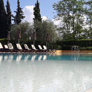 uma piscina com cadeiras e guarda-sóis e uma piscina em La Torre wine resort em Montecarlo