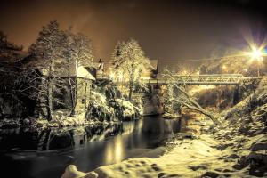 un puente sobre un río con nieve en el suelo en Apartments Strmac, en Slunj