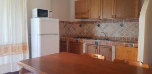a kitchen with a white refrigerator and a wooden table at Residence Spiaggia Bianca in Golfo Aranci