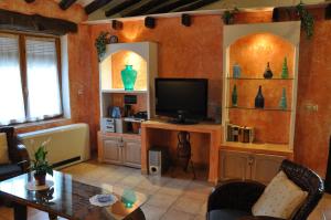 - un salon avec une télévision, une table et des chaises dans l'établissement Casa Rural El Pajar del Portalico, à Letur