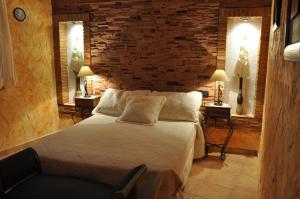 - une chambre avec un lit et un mur en briques dans l'établissement Casa Rural El Pajar del Portalico, à Letur