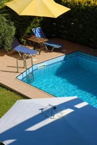 a swimming pool with two chairs and an umbrella at Villa SteMa in Xirokámbion