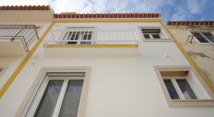 a white building with two windows and a balcony at Ferhouse Dreams Pátria in Nazaré