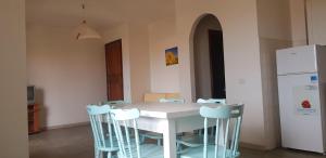 a kitchen with a white table with chairs and a refrigerator at Residence Spiaggia Bianca in Golfo Aranci
