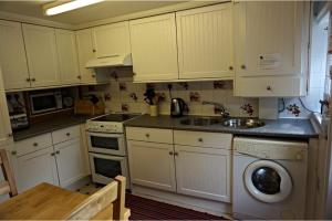 kuchnia z białymi szafkami, zlewem i zmywarką do naczyń w obiekcie Vale Cottage w mieście Middleham