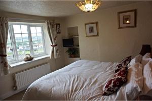 een slaapkamer met een wit bed en een raam bij Vale Cottage in Middleham