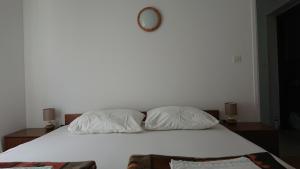 1 cama blanca con 2 almohadas y espejo en la pared en Apartman Kursar, en Srima