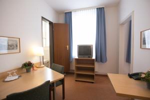 a room with a desk and a tv and a table at Rabes Hotel Kiel in Kiel