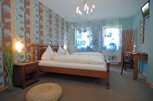 a bedroom with a bed and a desk and windows at Hotel & Restaurant 4 Winden in Windhagen