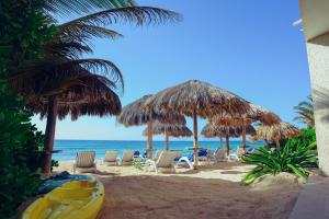 a beach with chairs and umbrellas and the ocean at Aquatech Villas DeRosa Resort in Akumal