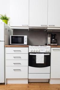 uma cozinha com um fogão branco e um micro-ondas em Orchidea Kamppi em Helsínquia