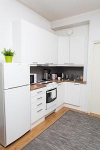 a white kitchen with white appliances and a rug at Orchidea Kamppi in Helsinki