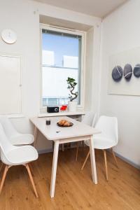 uma sala de jantar branca com uma mesa e cadeiras brancas em Orchidea Kamppi em Helsinque