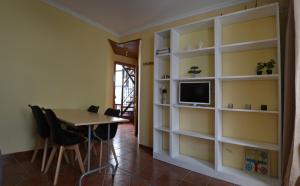 a dining room with a table and a tv and shelves at Calle Nueva 12 in Cazorla
