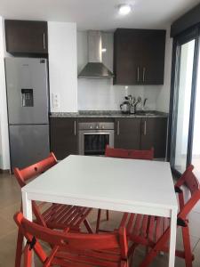 a kitchen with a white table and red chairs at Diamond Beach 2 in Burriana