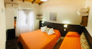 a bedroom with two beds with orange sheets at Dulce Atardecer in San José