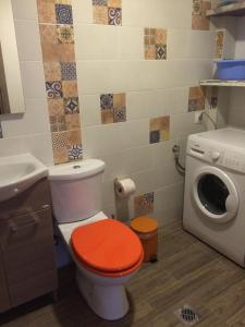 アギオス・ニコラオスにあるhouse chaidoのバスルーム(オレンジの蓋付きトイレ、洗濯機付)