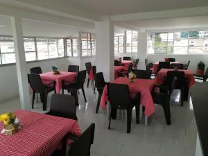 una sala da pranzo con tavoli rossi e sedie nere di Torre De Granada a Cali