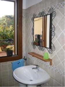 a bathroom with a sink and a mirror and a window at Appartamenti Le Cicale in Fertilia