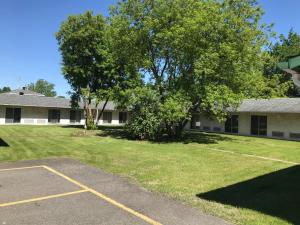 a building with a tree and a parking lot at Motel la Siesta de Gascon in Terrebonne