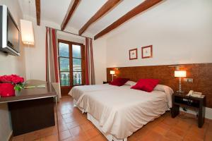 a bedroom with a large white bed with red pillows at Hotel y Apartamentos DES PUIG in Deia